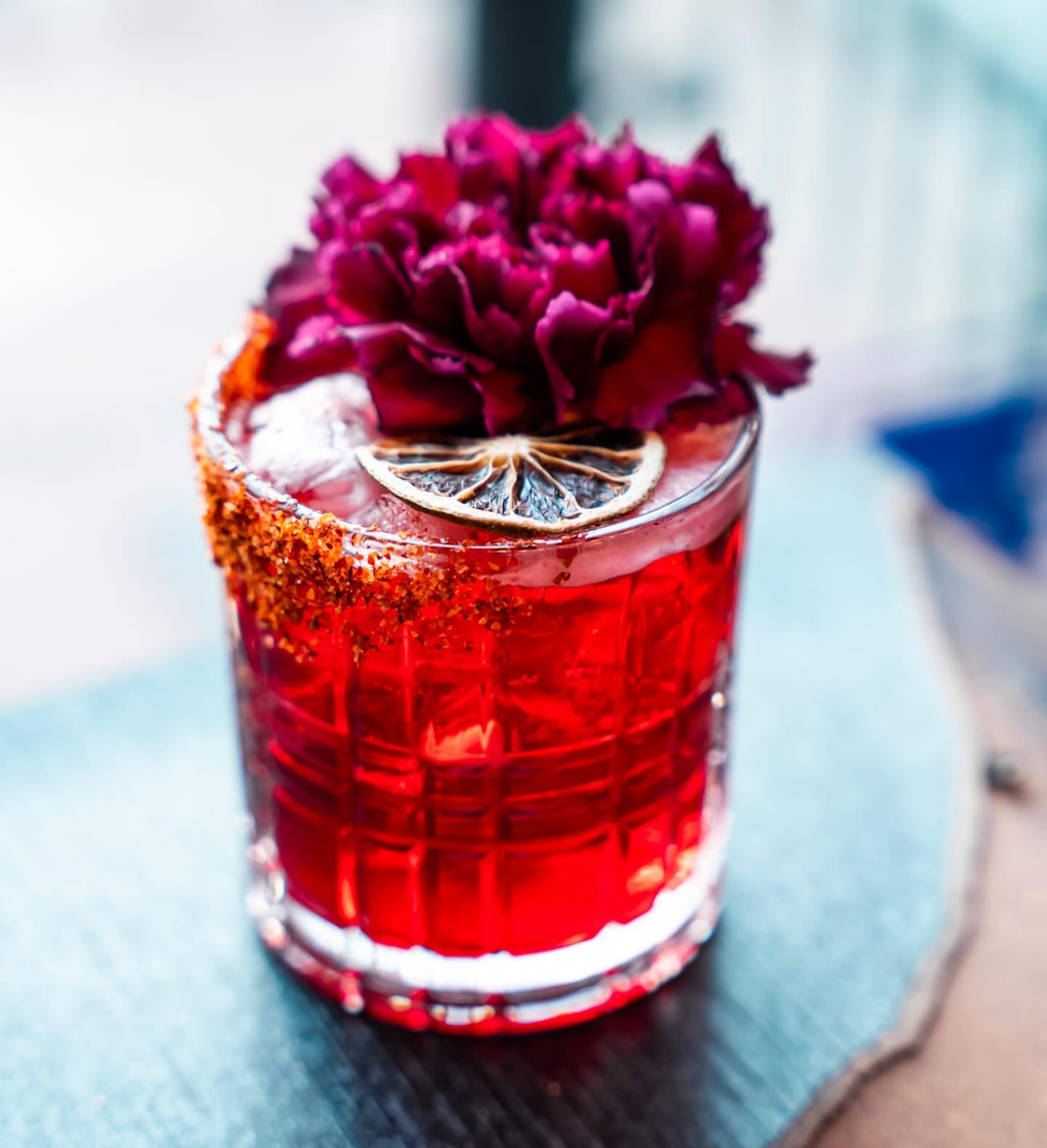 Red cocktail with dried citrus and floral garnish